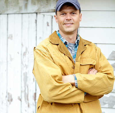 Buy stock photo Portrait of a smiling man with his arms crossed standing outside a shed