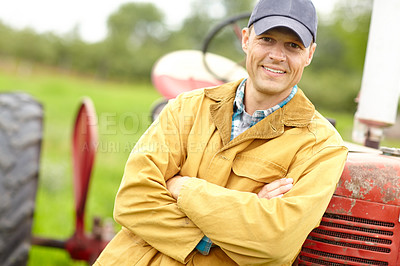 Buy stock photo Portrait of a smiling farmer with his arms crossed standing infront of his tractor