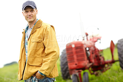 Buy stock photo Portrait of a farmer standing in a field with a tractor behind him