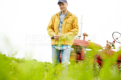 Buy stock photo Portrait of a farmer standing in a field with his tractor parked behind him - Copyspace