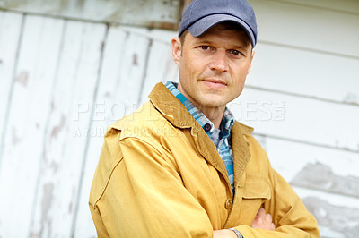 Buy stock photo Man, farmer and outdoor with arms crossed in portrait by barn, cap and confident for job in countryside. Person, agriculture and pride for job by shed with sustainable small business in New Zealand