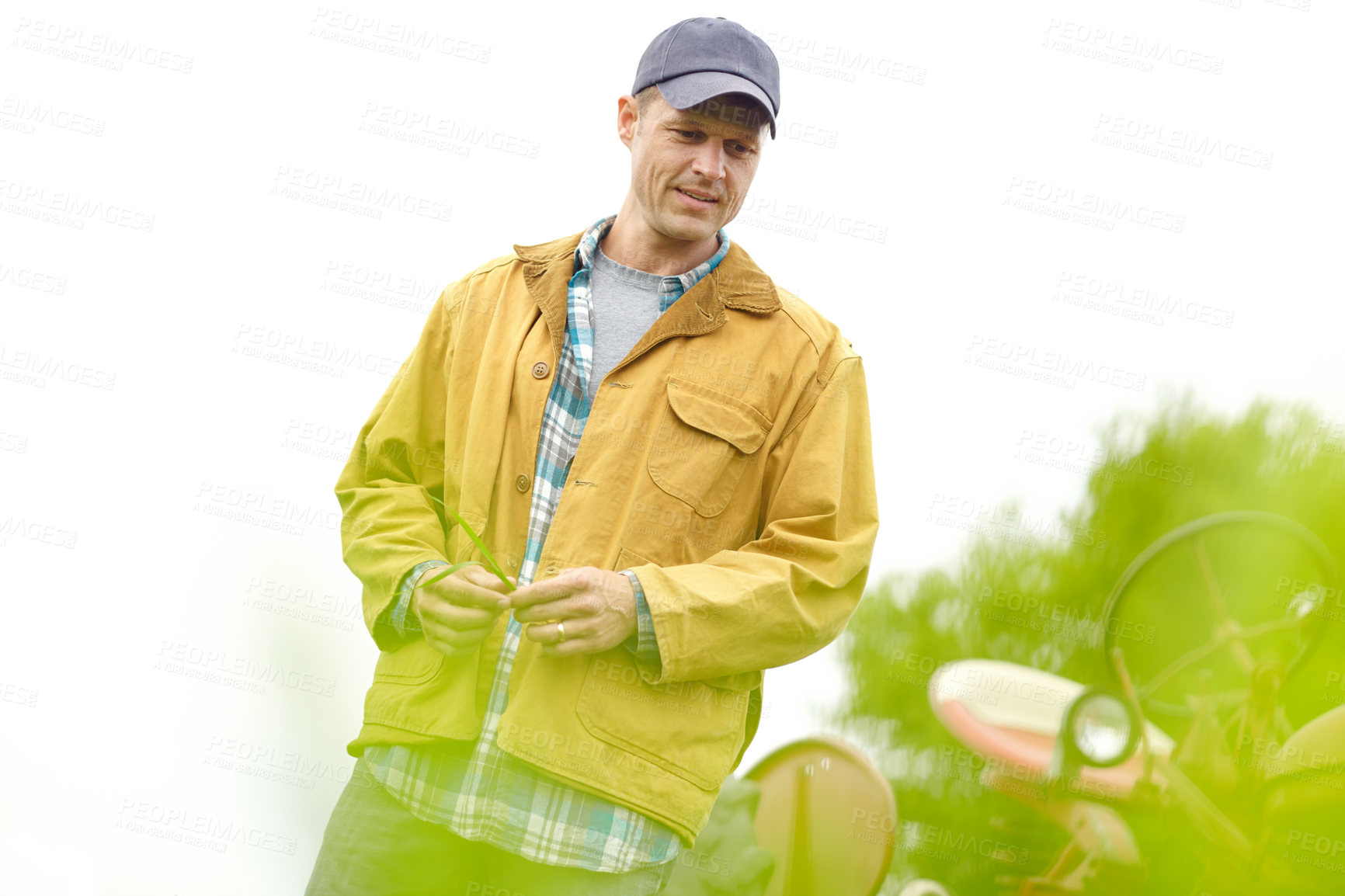 Buy stock photo Shot of a farmer standing in a field with his tractor behind him with copyspace