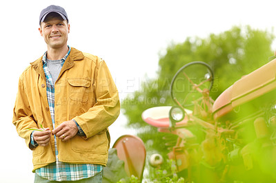 Buy stock photo Portrait of a smiling farmer standing next to his tractor in a field