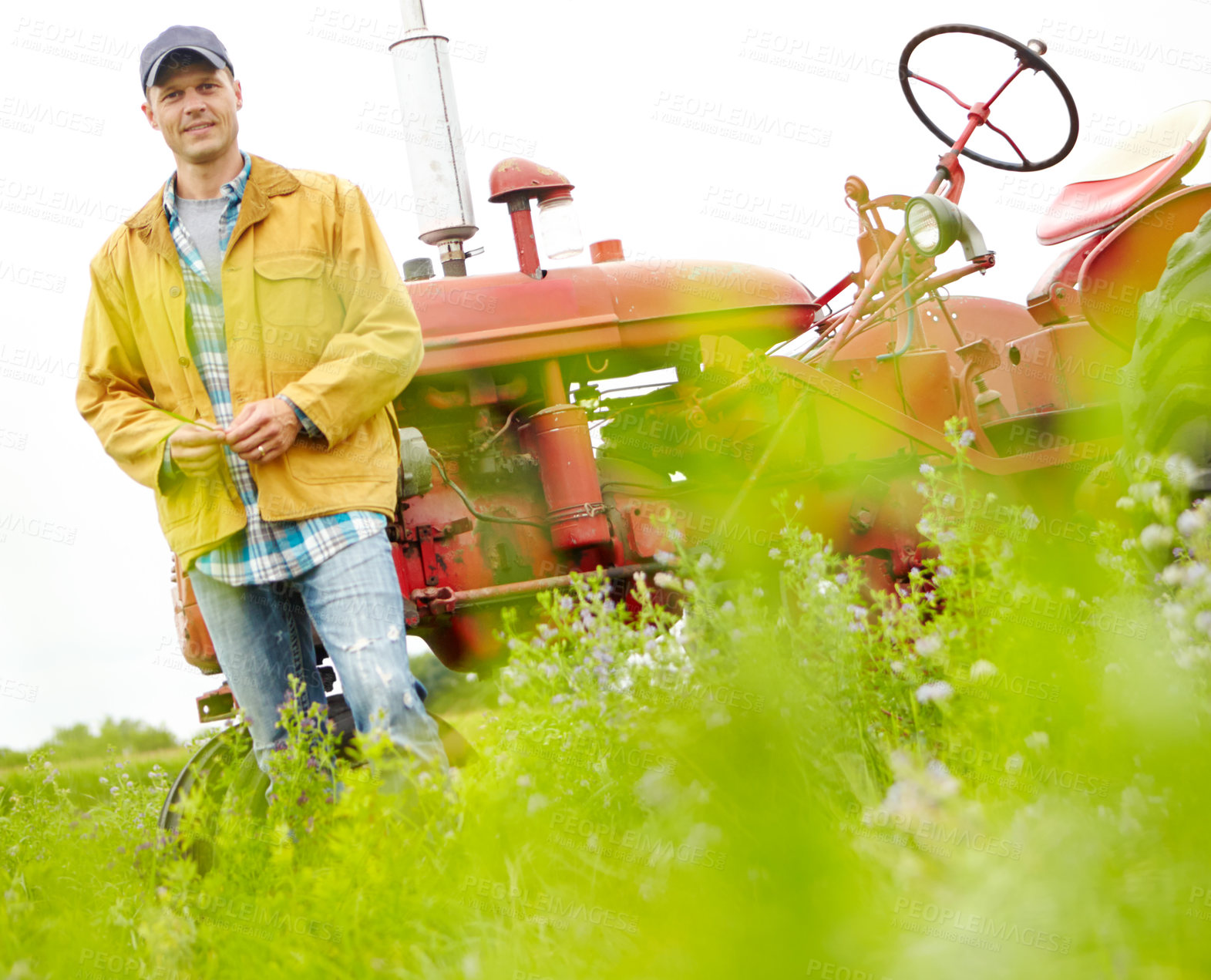 Buy stock photo Portrait of a smiling farmer standing next to his tractor in a field