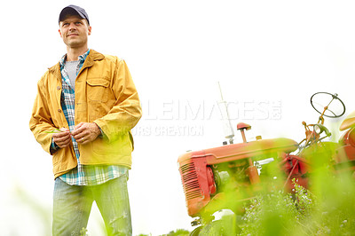 Buy stock photo A farmer standing in a field with his tractor parked behind him - Copyspace