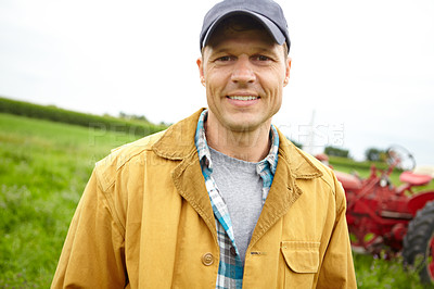 Buy stock photo Portrait of a happy farmer in a field with a tractor parked behind him - Copyspace