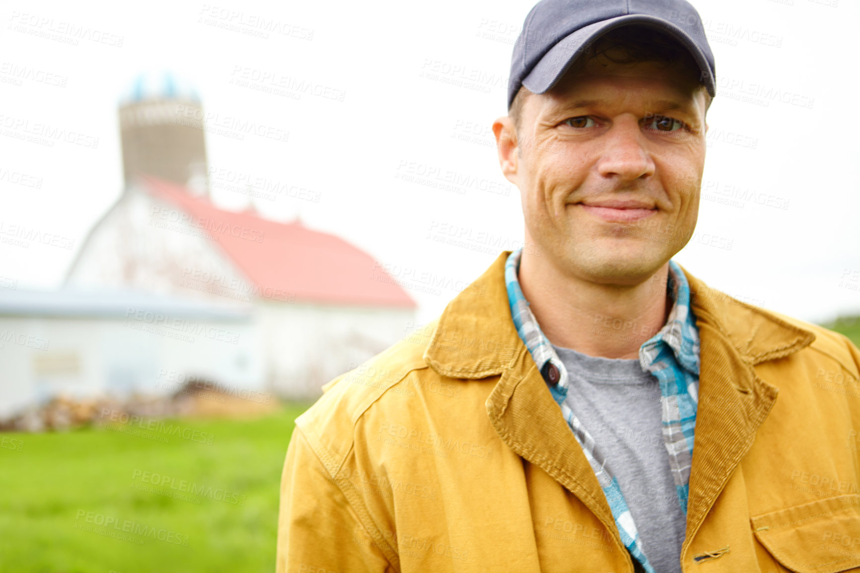 Buy stock photo A mid adult farmer standing on the farm with the farm house in the background