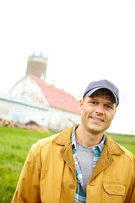 Buy stock photo A mid adult farmer standing on the farm with the farm house in the background