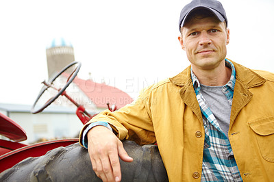 Buy stock photo A mid adult farmer leaning against a tractor on his farm