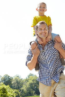 Buy stock photo Young father carrying his son on his shoulders outdoors
