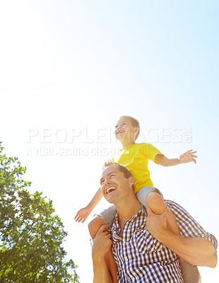 Buy stock photo Cute young boy being carried on his father's shoulders and smiling widely