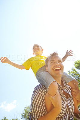Buy stock photo Young father laughing outdoors while his son sits on his shoulders