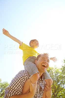 Buy stock photo Cute young boy with his arms outstretched while sitting on his father's shoulders and laughing