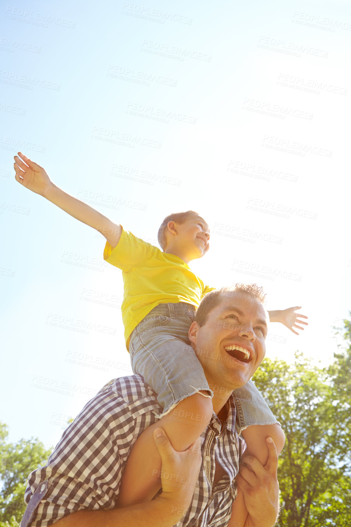 Buy stock photo Cute young boy with his arms outstretched while sitting on his father's shoulders and laughing