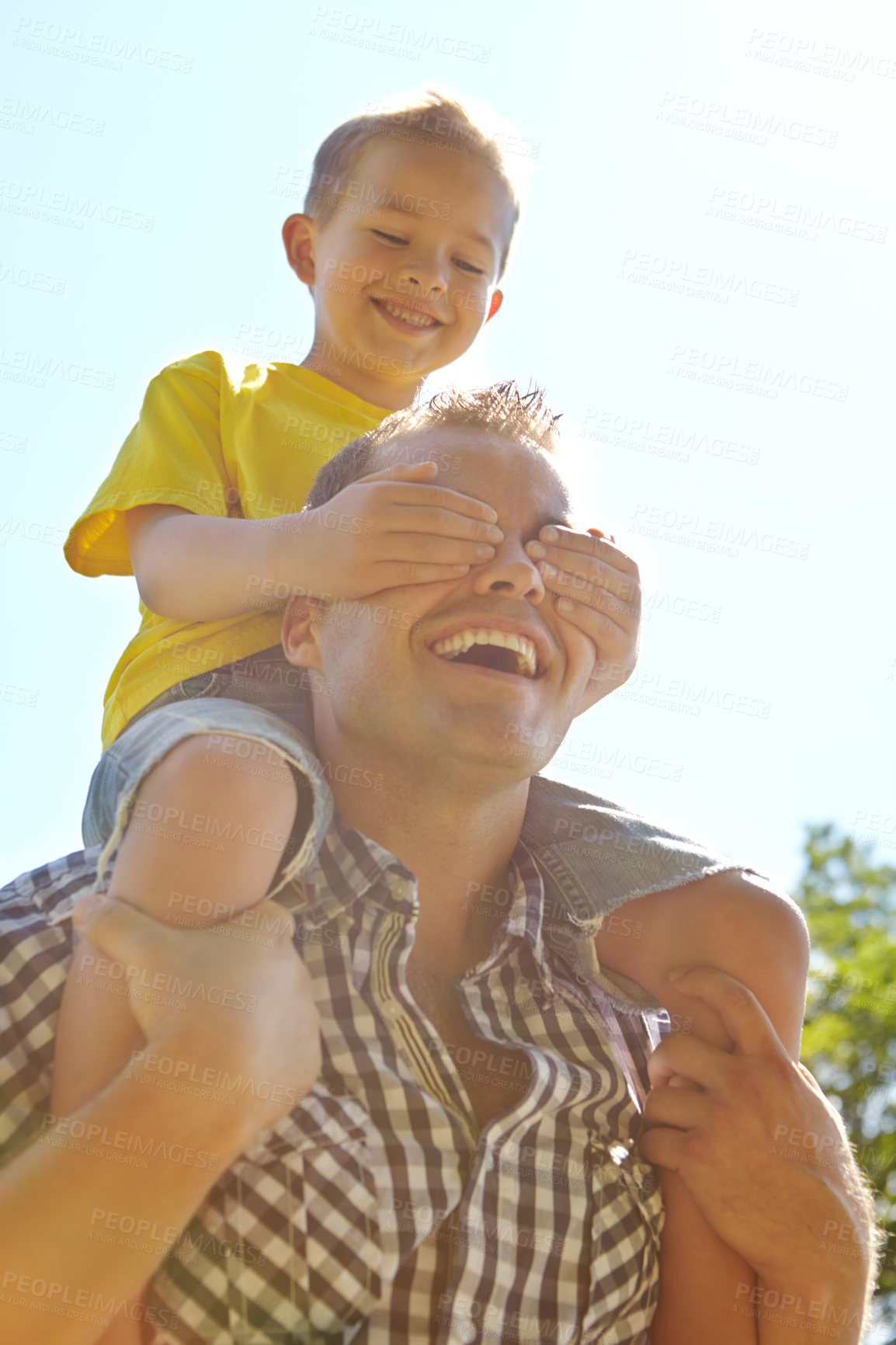 Buy stock photo Cropped shot of a cute young boy covering up his dad's eyes while sitting on his shoulders