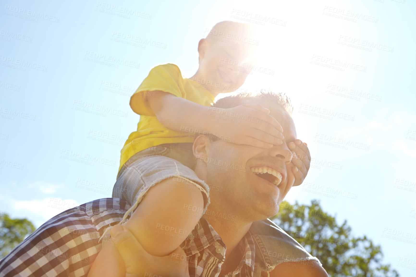Buy stock photo Cropped shot of a cute young boy covering up his dad's eyes while sitting on his shoulders