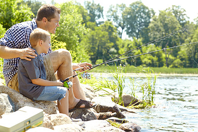 Buy stock photo Young father sitting beside his son and fishing