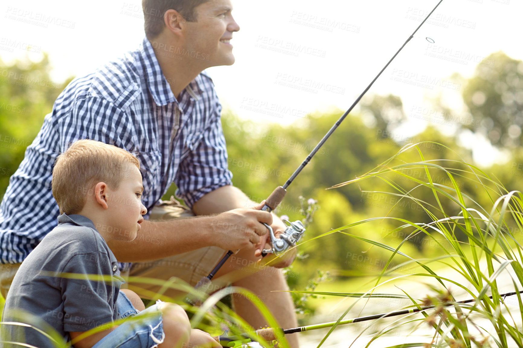 Buy stock photo Side view of a cute young boy sitting with his dad waiting to catch a fish