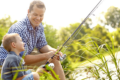Buy stock photo Father and son sitting together beside a lake with their fishing rods