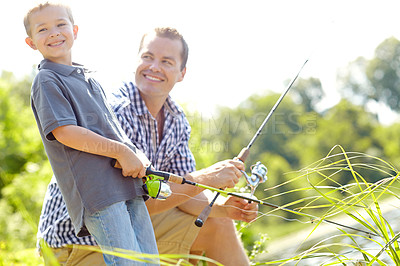 Buy stock photo Young father smiling with his son while holding their fishing rods beside a lake