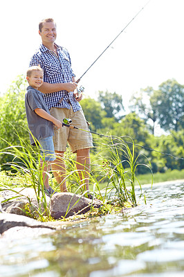 Buy stock photo Cute young boy standing by a lake with his dad and fishing