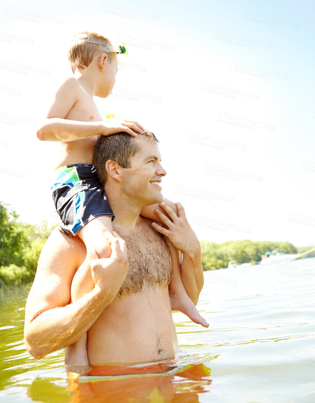 Buy stock photo Cute young boy sitting on his dad's shoulders while wearing a snorkel and mask