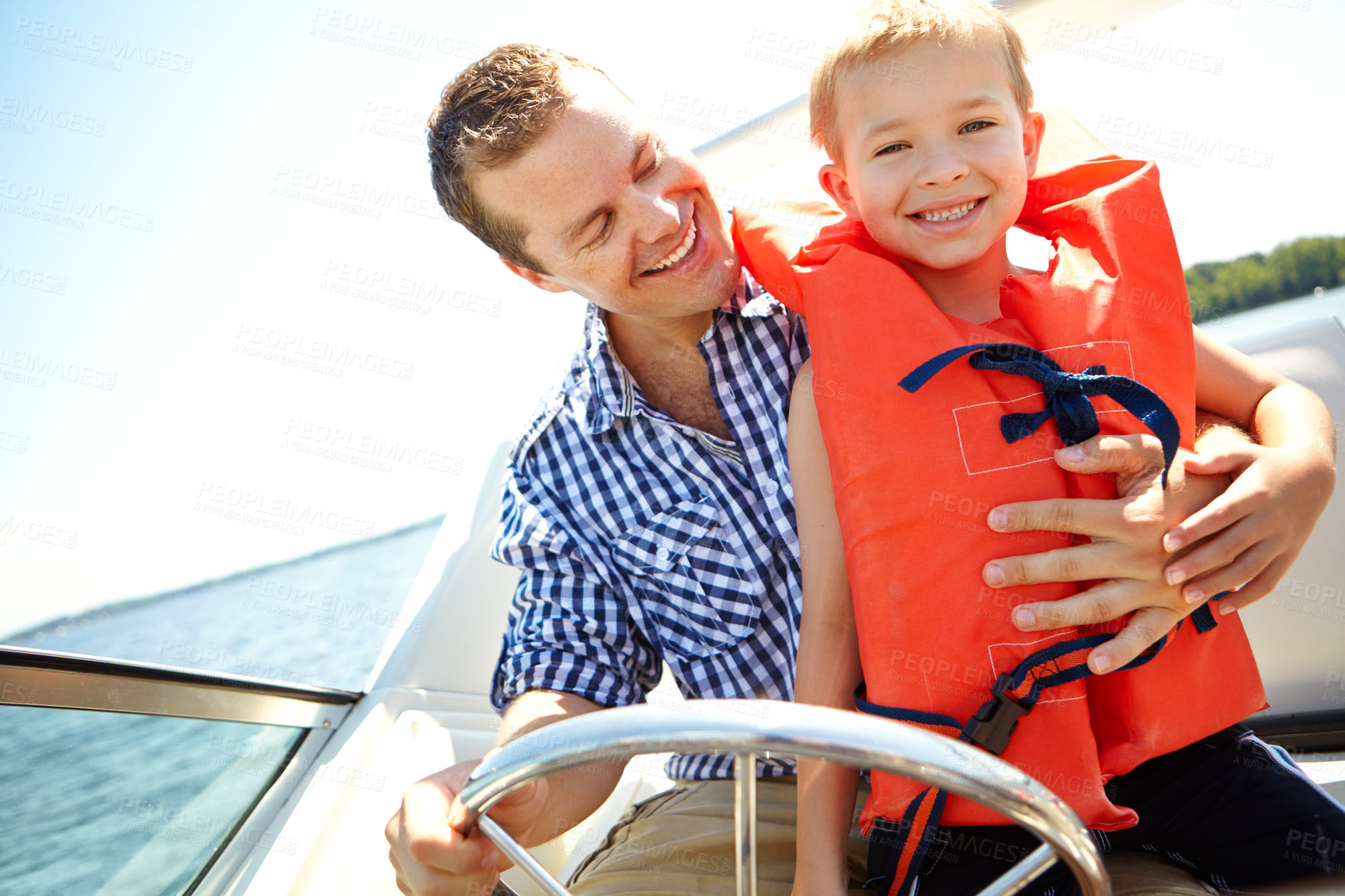 Buy stock photo Young father and his son riding in a speedboat together on a lake