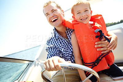 Buy stock photo Young father and son laughing while riding in a speedboat