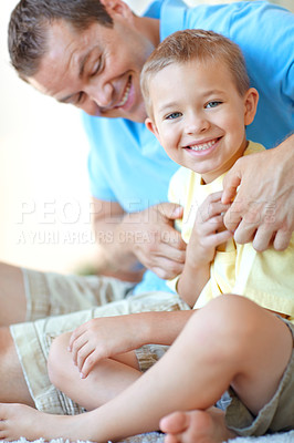 Buy stock photo Boy, father and tickling in portrait on floor with care, bonding and love with games, funny or connection in home. Child, dad and happy with comic memory, relax or together at family house in Germany