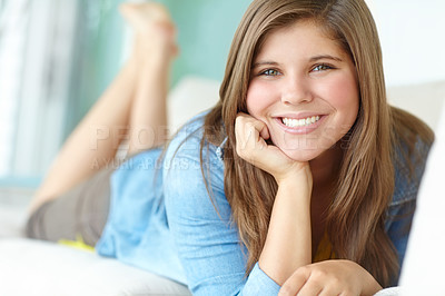 Buy stock photo Girl, portrait and teenager lying in home, peace and confident adolescent in living room. Female person, comfortable kid and proud smile on weekend in apartment, resting and morning satisfaction