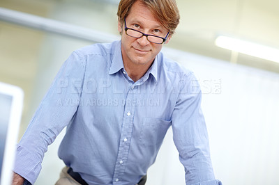 Buy stock photo Attractive, mature businessman standing in an office wearing glasses while smiling