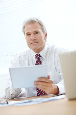 Buy stock photo Head and shoulders shot of a mature employee holding a tablet while looking away from the camera