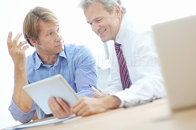 Buy stock photo Two male colleagues in a meeting with a digital presentation on a tablet