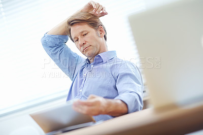 Buy stock photo Mature businessman thinking about the contents on a tablet