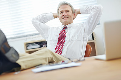 Buy stock photo Mature, attractive business associate sitting back in an office chair with his hands behind his head