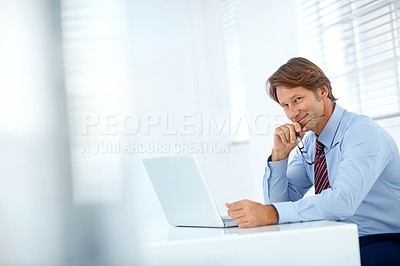 Buy stock photo Portrait of a mature businessman working at his laptop