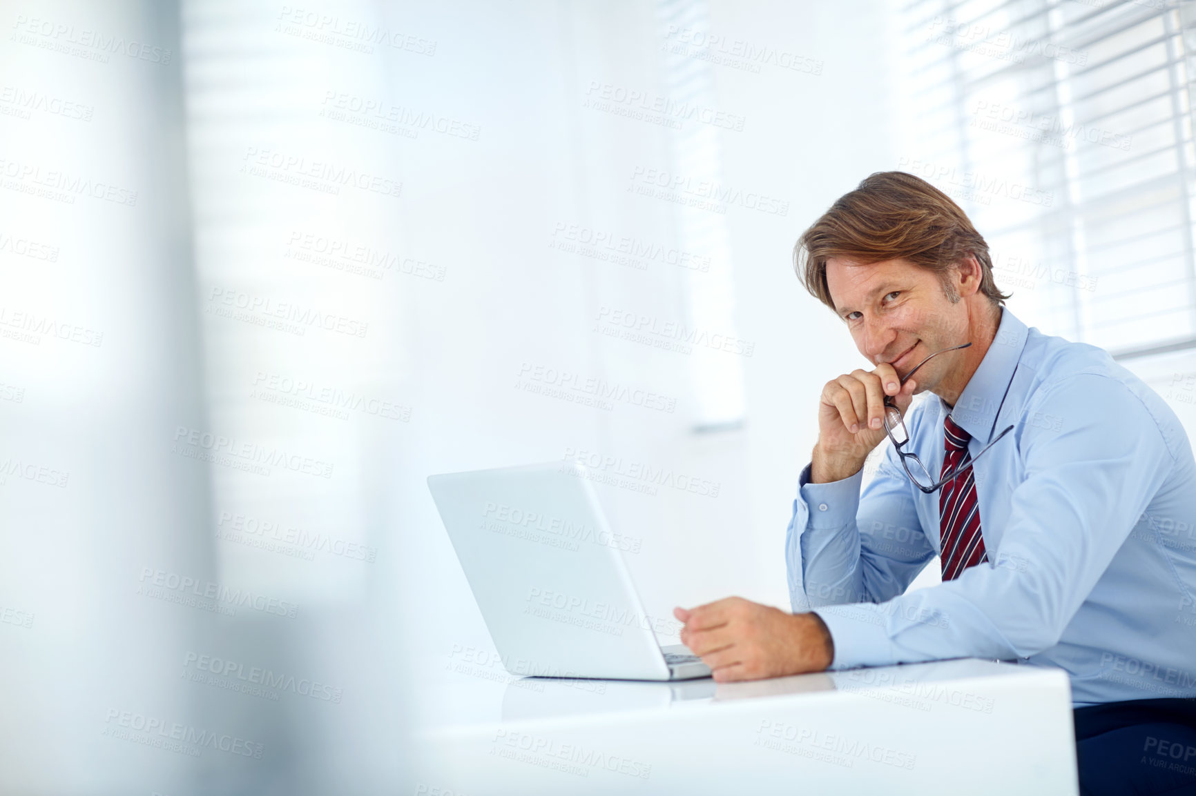 Buy stock photo Portrait of a mature businessman working at his laptop