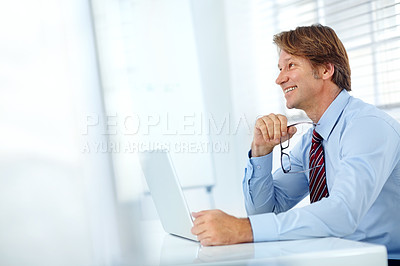 Buy stock photo Profile shot of a smiling mature businessman working at his laptop