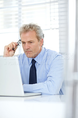 Buy stock photo Shot of a mature businessman thinking while sitting in front of his laptop