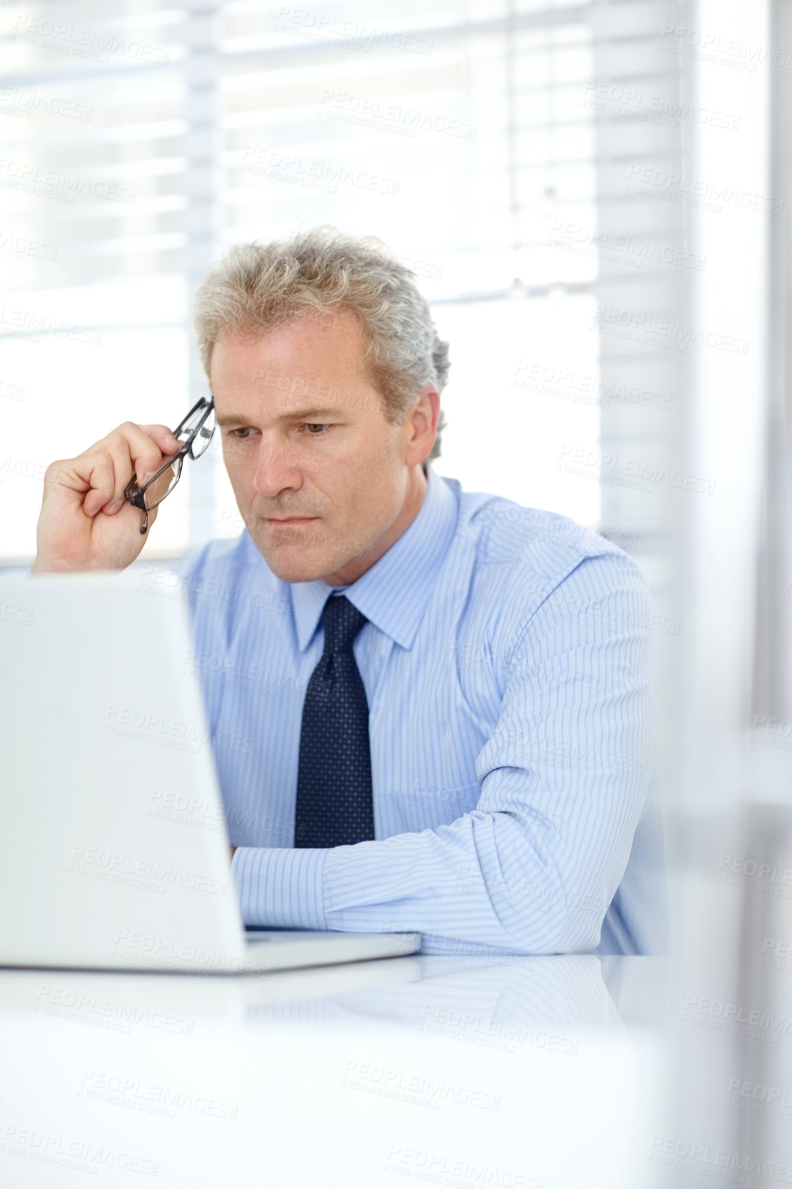 Buy stock photo Shot of a mature businessman thinking while sitting in front of his laptop