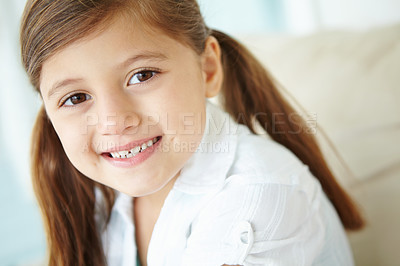 Buy stock photo Girl, happy and portrait of child in home for fun on weekend in living room of house on sofa. Smile, satisfaction and face of female kid alone on couch for happiness, comfort and childhood in Spain