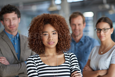 Buy stock photo Serious young businesswoman looking at the camera with colleagues behind her