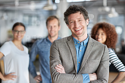 Buy stock photo Handsome man smiling at the camera with colleagues behind him