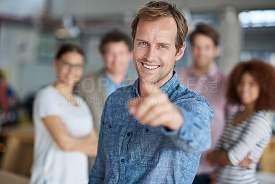 Buy stock photo Smiling man pointing at you a friendly group of office staff in the background