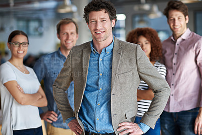 Buy stock photo Smiling mature man posing confidently with colleagues in the background