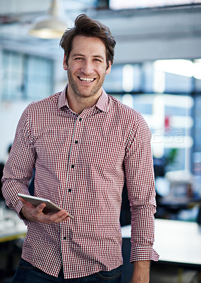 Buy stock photo Portrait of a handsome man smiling at the camera while holding his digital tablet in an open office space