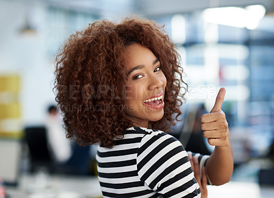 Buy stock photo Young woman giving a thumbs up over her shoulder to you in an open office space