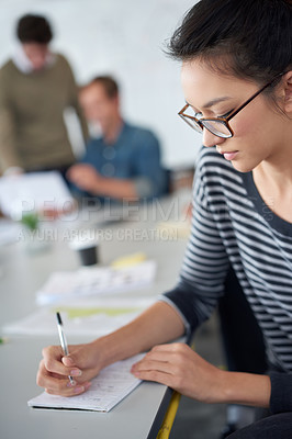 Buy stock photo Shot of an attractive young woman working in an office with colleagues in the background