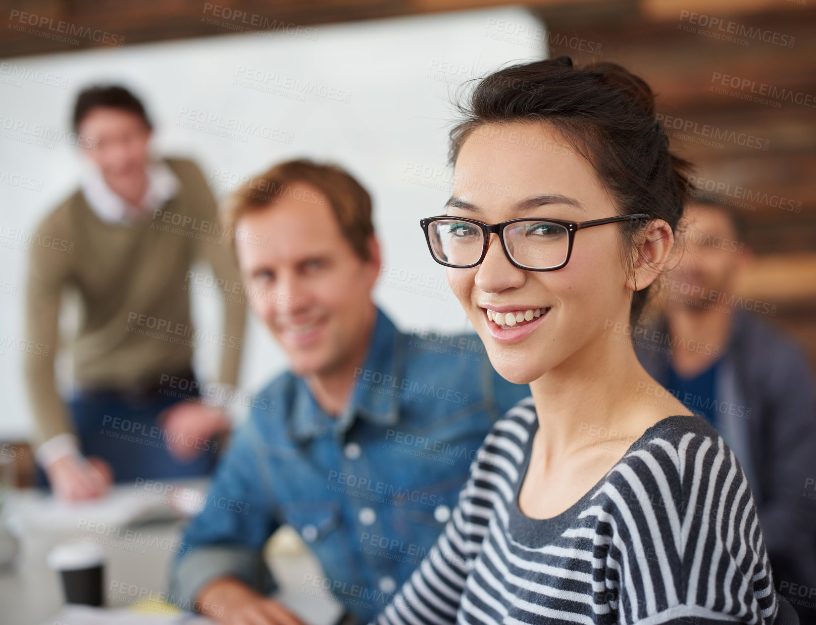 Buy stock photo Portrait of an attractive young woman sitting in an office with colleagues in the background