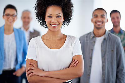Buy stock photo Young confident businesswoman smiling at the camera with colleagues standing behind her